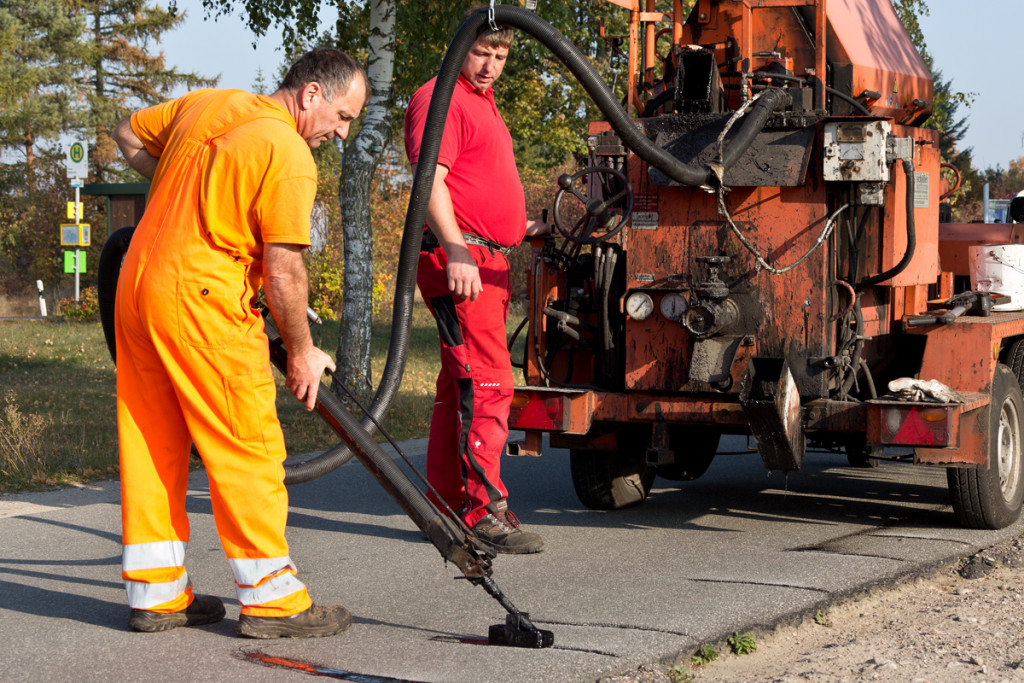 Mitarbeiter von MOT verfüllen Risse mit Schlauch und Lanze