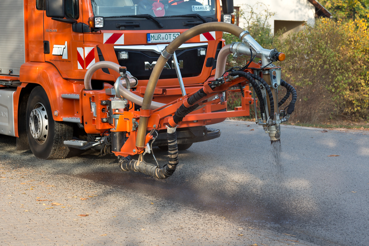 Fahrzeug von MOT mit Spritzarm flickt Schlaglöcher in einer Ortsstraße